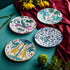 The Explorer Side Plates designed by Emma J Shipley, crafted in fine bone china by skilled artisans in Stoke on Trent UK, hand decorated with an exquisitely detailed and colourful design featuring leopard spotted elephants, a leaping gazelle, soaring hornbills in layers of teal, greens and neutrals, part of the Fine China Dining collection