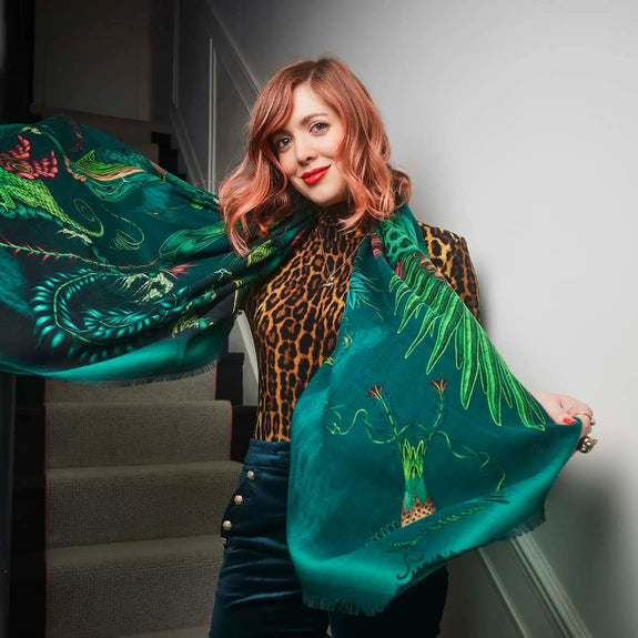 Teal | Photo of Emma next to staircase wearing the Quetzal fine wool scarf in Teal, designed by Emma J Shipley in London featuring Quetzal bird, amongst foliage and other birds