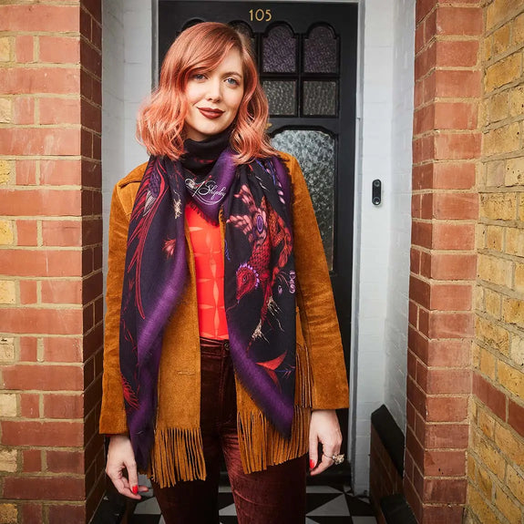 Violet | Photo of Emma outside house wearing the Quetzal Fine wool scarf in Violet, designed by Emma J Shipley in London featuring Quetzal bird, amongst foliage and other birds
