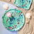 Decorative trays with ocean-themed designs on a sandy surface with shells.