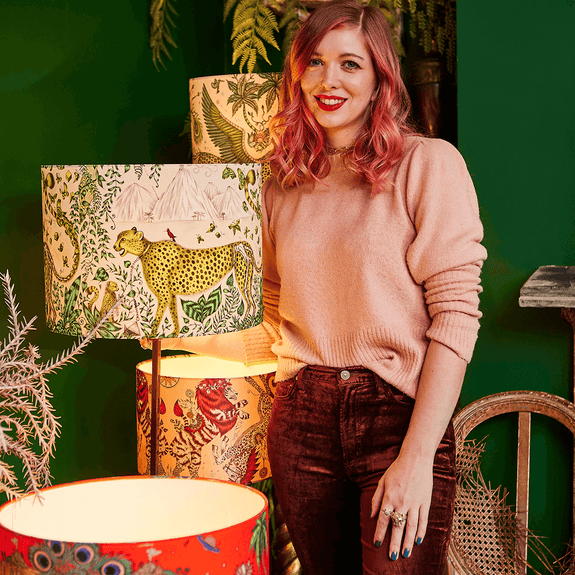 Emma J Shipley with her Cheetah Silk Lampshade showing of the green and golden yellow details as well as the cheetah and foliage running through the design