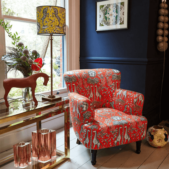 Flame | Kruger Dalston Armchair shown in a living environment, the striking red colour way stands out and the animal print evokes an african safari