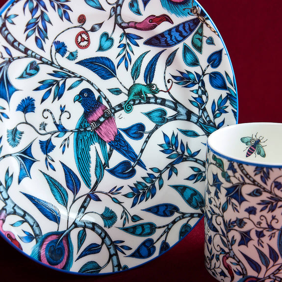 Detail of the Rousseau Side Plate designed by Emma J Shipley, crafted in fine bone china by skilled artisans in Stoke on Trent UK, hand decorated with an exquisitely detailed and colourful scene of curious birds and creatures amongst a pattern of winding foliage in a palette of blues, and subtle pink blush tones, part of the Fine China Dining collection