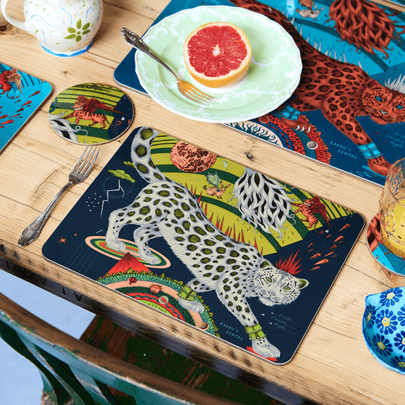 Forest | Medium | 1 | A lifestyle image of the Forest Medium Placemat in the snow leopard design with a beige leopard surrounded by bright lime greens and deep dark forest tones, designed by Emma J Shipley