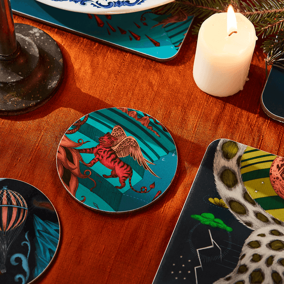 Teal | A lifestyle shot of the Teal Snow Leopard coaster with the red winged lion on, inspired by His Dark Materials