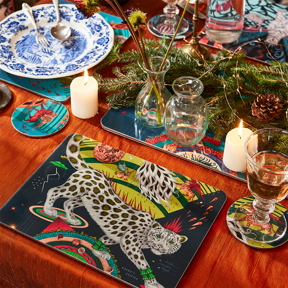 Forest | Medium | 1 | A lifestyle image of the Forest Medium Placemat in the snow leopard design with a beige leopard surrounded by bright lime greens and deep dark forest tones, designed by Emma J Shipley