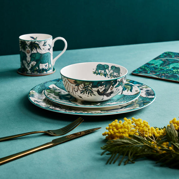 The Zambezi Dinner Set designed by Emma J Shipley, crafted in fine bone china by skilled artisans in Stoke on Trent UK, hand decorated with an exquisitely detailed and colourful design featuring leopard spotted elephants, a leaping gazelle, soaring hornbills in layers of teal, greens and neutrals, part of the Fine China Dining collection
