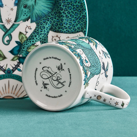 1 | Bottom of the Zambezi Mug handle designed by Emma J Shipley, crafted in fine bone china by skilled artisans in Stoke on Trent UK, hand decorated with an exquisitely detailed and colourful design featuring leopard spotted elephants, a leaping gazelle, soaring hornbills in layers of teal, greens and neutrals, part of the Fine China Dining collection